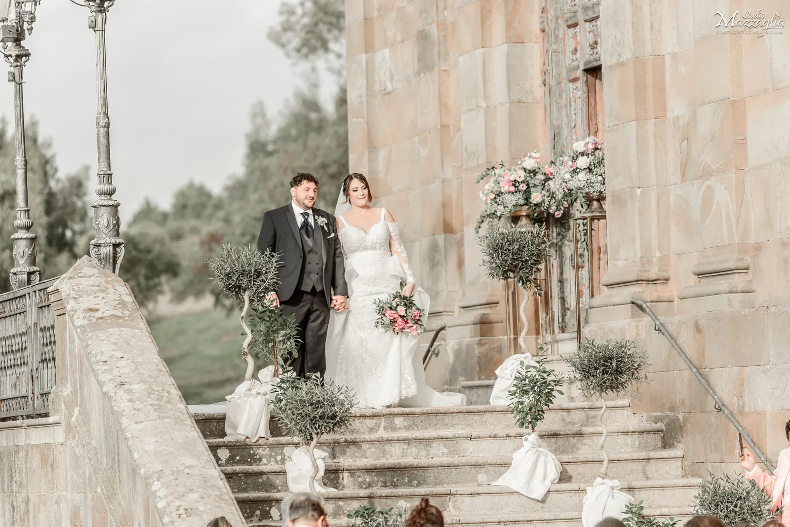 Sposi si tengono per mano sulla scalinata esterna del Santuario di Tagliavia a Corleone subito dopo la cerimonia di matrimonio.