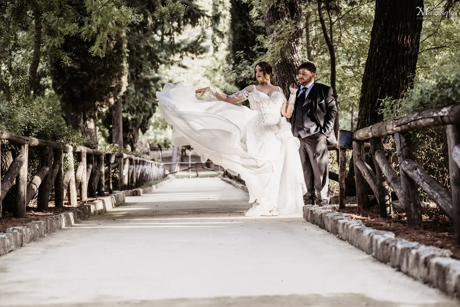 Servizio fotografico di matrimonio nel bosco di Ficuzza, con la sposa che fa volteggiare l'abito sul sentiero alberato accanto allo sposo.