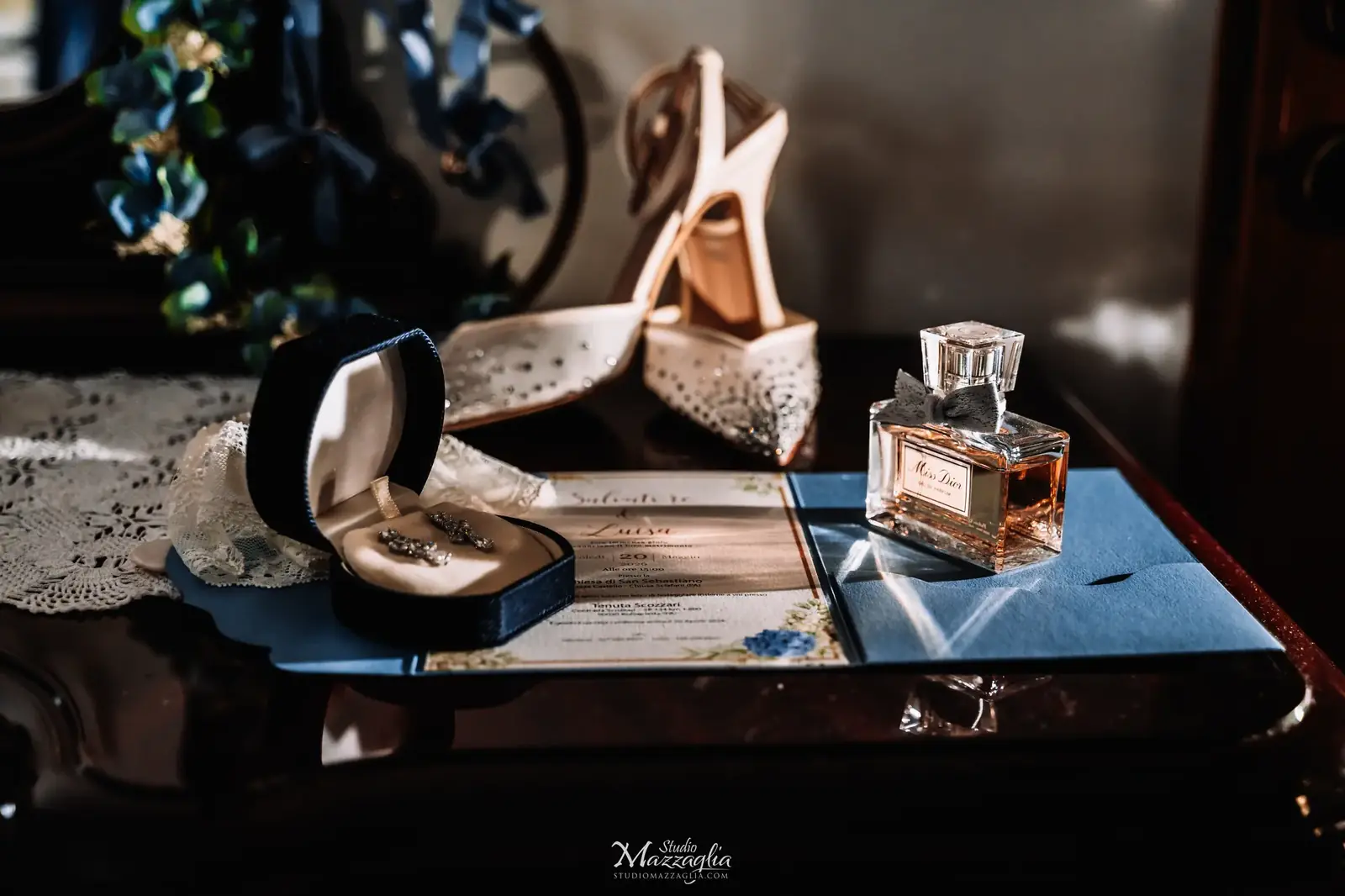 Still life fotografico degli accessori sposa con profumo Miss Dior e scarpe con brillantini durante i preparativi di un matrimonio in Sicilia.