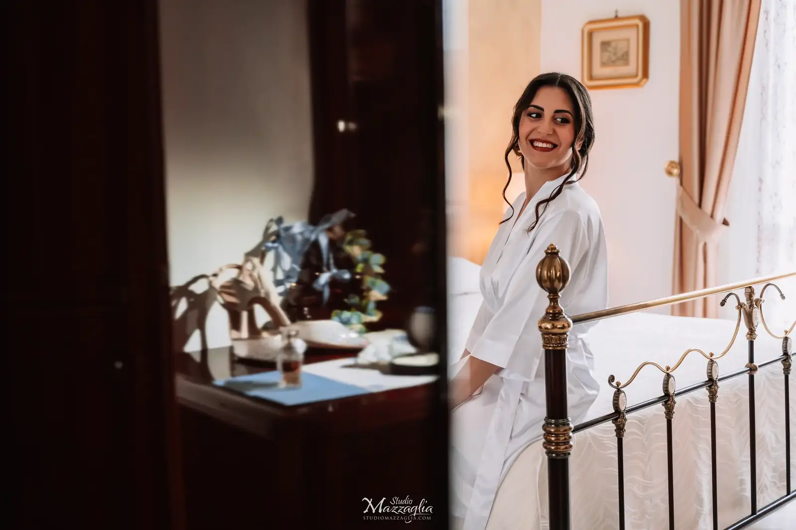 Sposa Luisa sorridente guarda l'abito nuziale sul letto