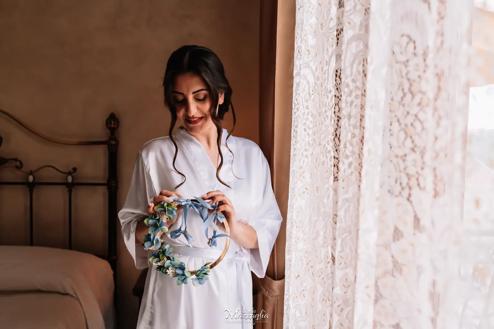 Sposa seduta sul letto con cerchio floreale azzurro