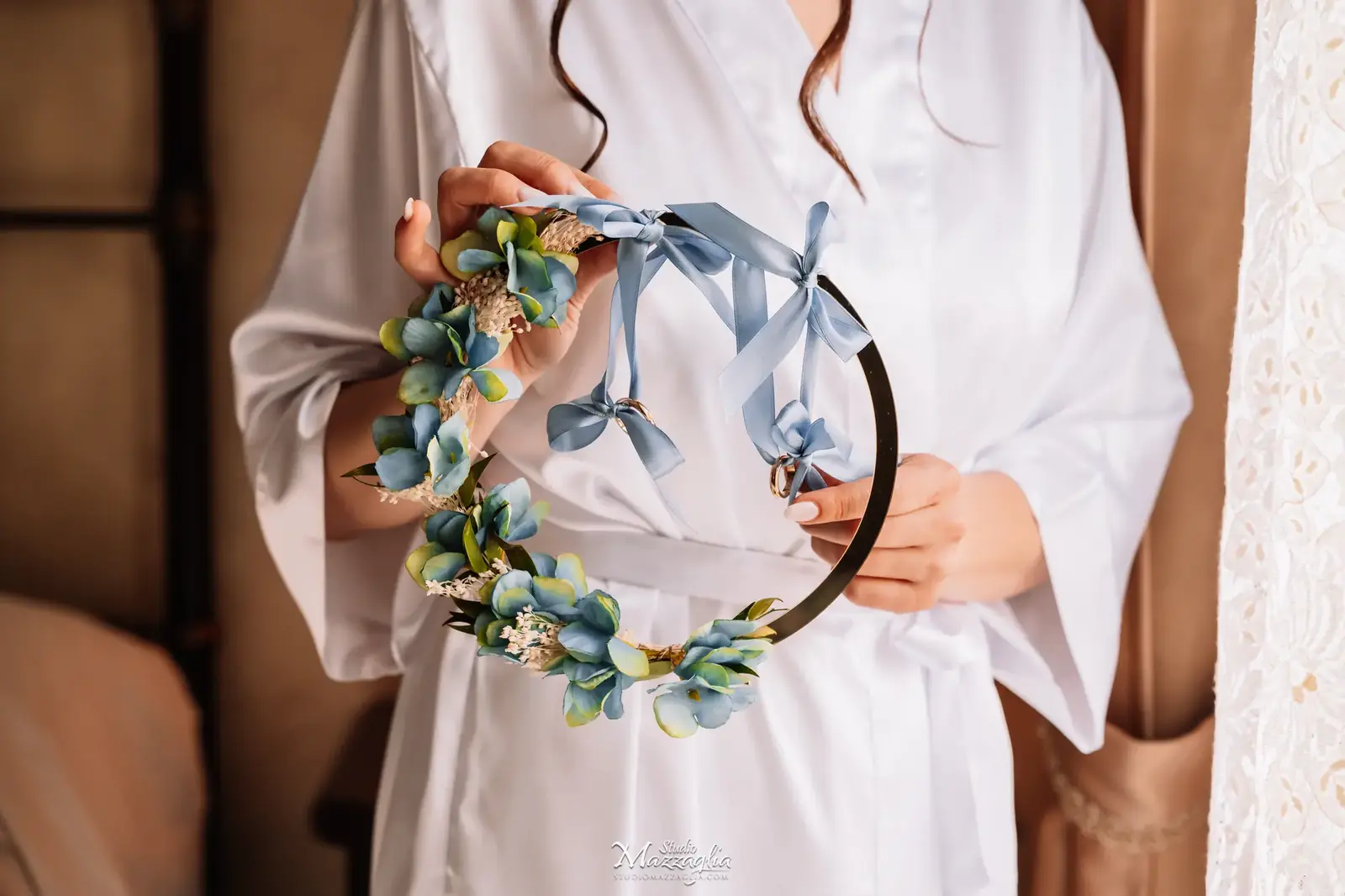 Mani della sposa tengono il cerchio di fiori blu