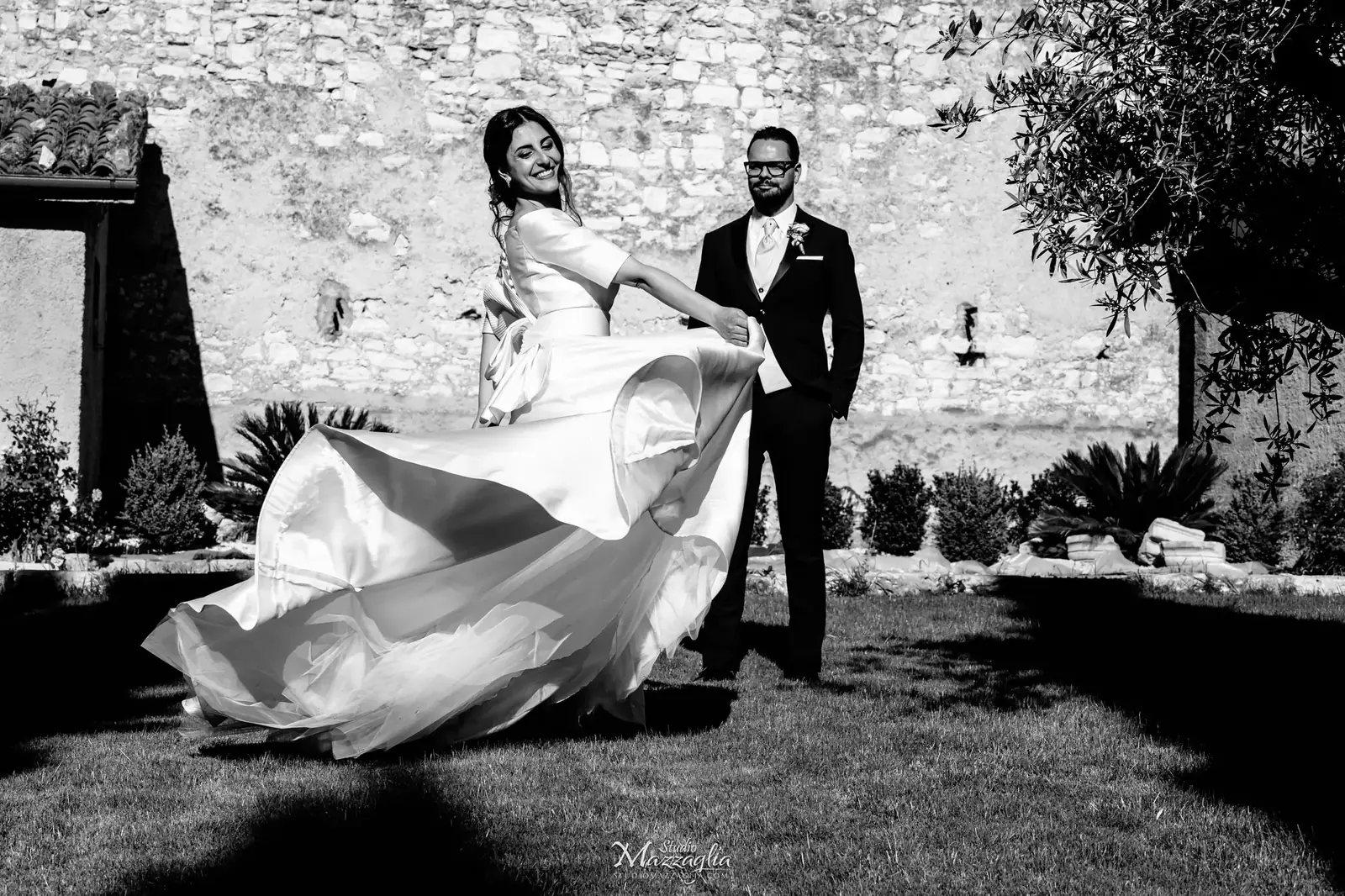Sposi si baciano nel cortile in pietra in bianco e nero