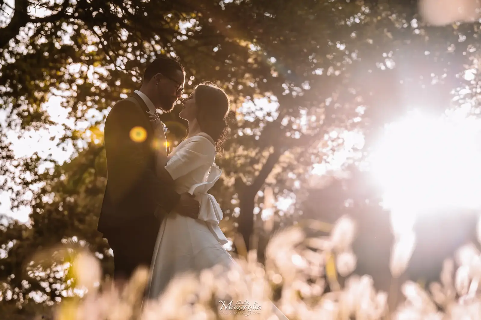 Abbraccio intimo degli sposi controluce con lens flare dorato