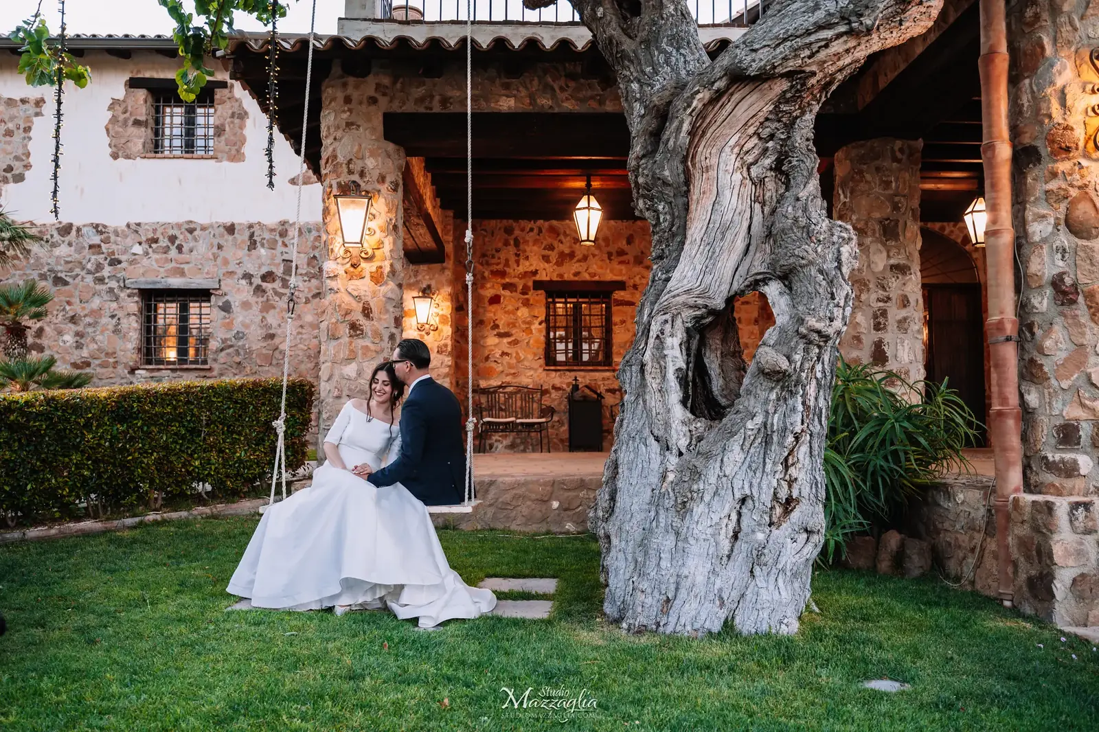 Sposa Luisa seduta sull'altalena d'albero con lo sposo vicino