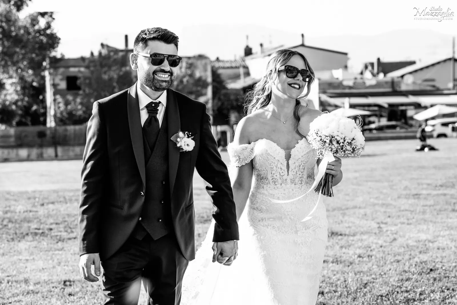 Fotografo matrimonio Palermo: sposi Marianna e Mario camminano mano nella mano con occhiali da sole in un reportage in bianco e nero