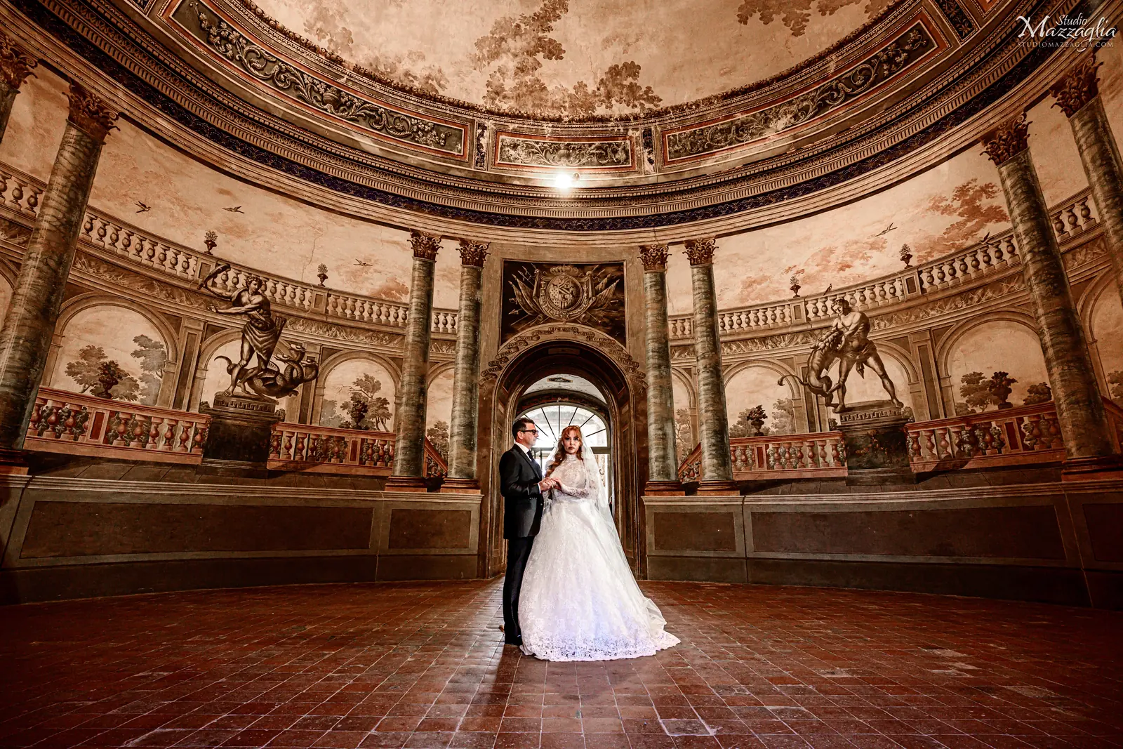 Sposi Iryna e Antonino scendono la scalinata barocca di Villa Palagonia a Bagheria - Fotografo matrimonio Studio Mazzaglia Palermo.